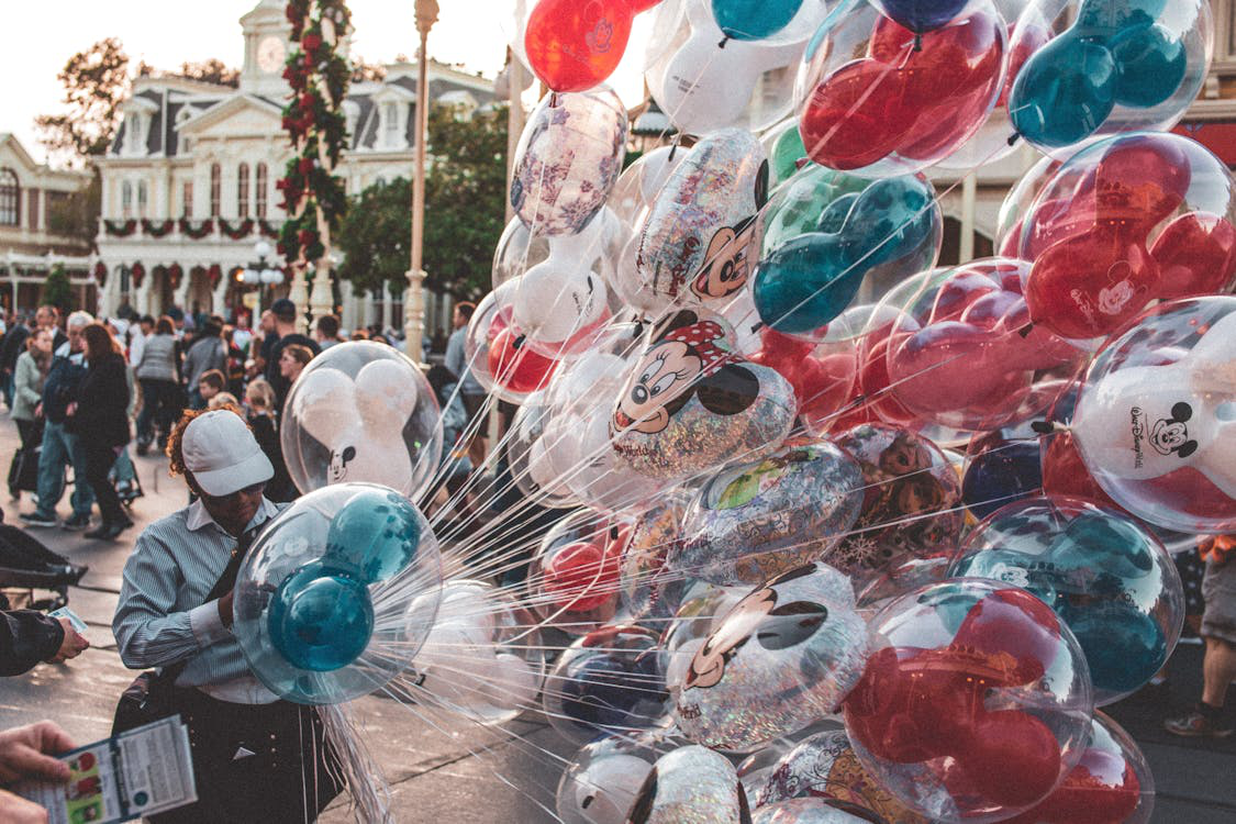 a balloon vendor wearing a white cap.