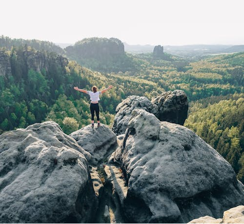 A woman standing on a rock formation in the Elbe Sandstone Mountains